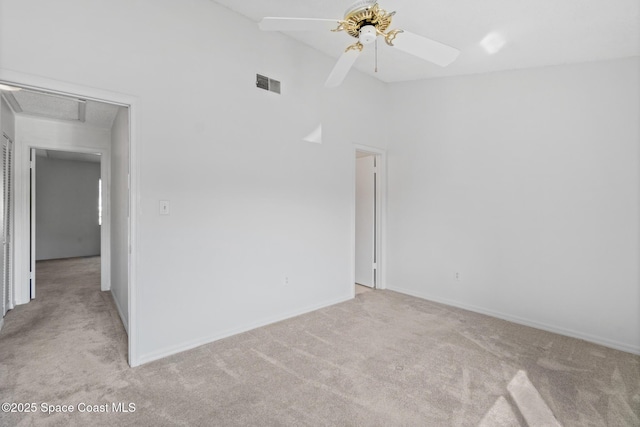 empty room with ceiling fan, light colored carpet, and high vaulted ceiling