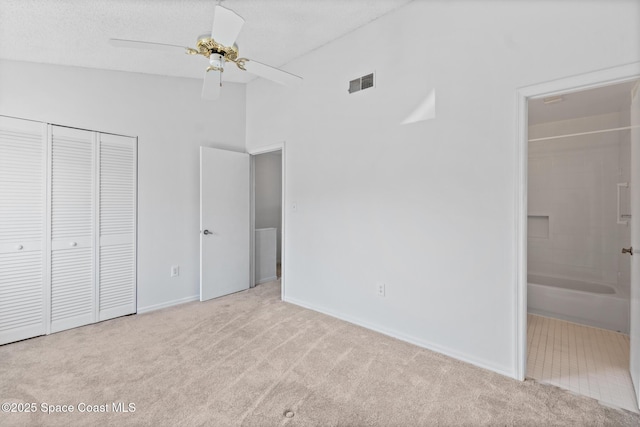 unfurnished bedroom with ensuite bath, ceiling fan, high vaulted ceiling, light carpet, and a closet