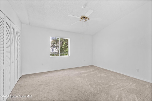 unfurnished bedroom featuring a textured ceiling, light colored carpet, a closet, and ceiling fan