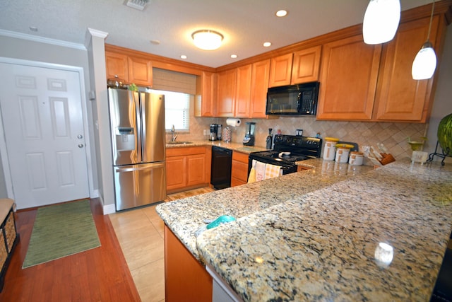 kitchen featuring black appliances, backsplash, ornamental molding, light stone counters, and kitchen peninsula