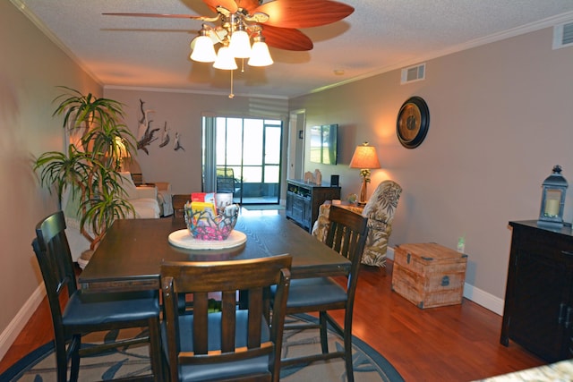 dining area featuring ornamental molding, wood-type flooring, and a textured ceiling