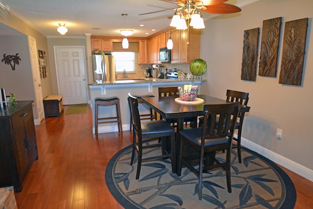 dining room with sink, crown molding, and dark wood-type flooring