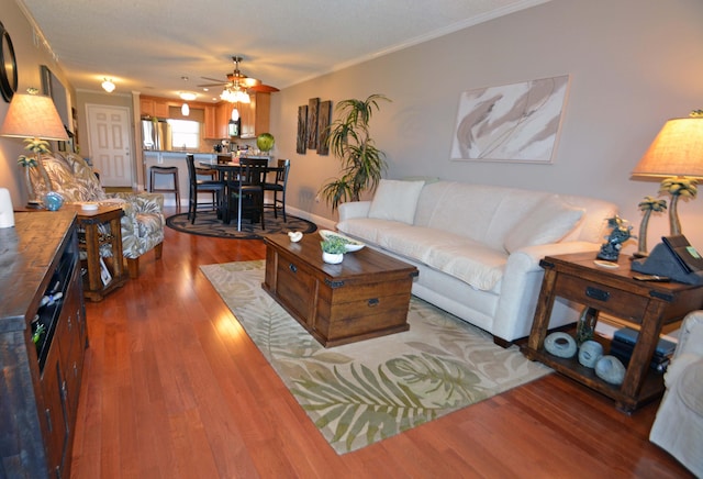 living room featuring hardwood / wood-style flooring, ornamental molding, ceiling fan, and a textured ceiling