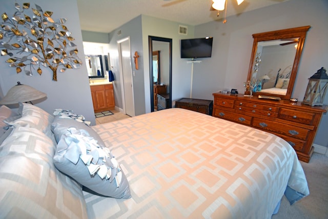 bedroom featuring ceiling fan, ensuite bath, and light colored carpet