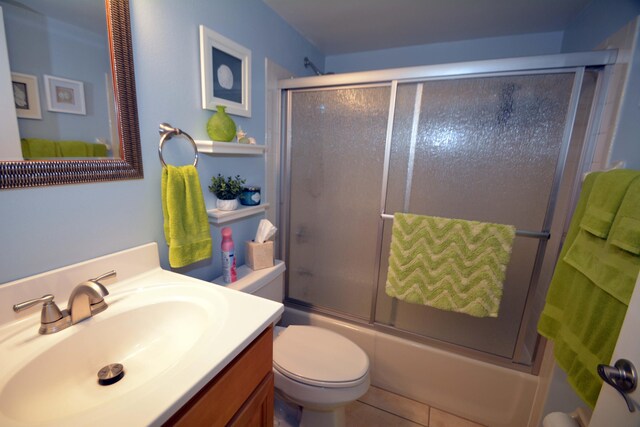 full bathroom with enclosed tub / shower combo, vanity, tile patterned flooring, and toilet