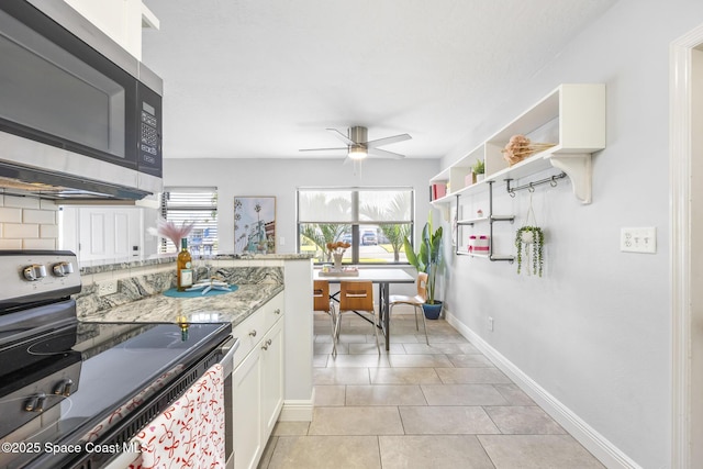 kitchen with appliances with stainless steel finishes, white cabinets, backsplash, light tile patterned floors, and light stone countertops