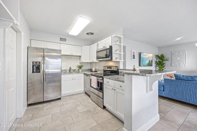 kitchen featuring light stone counters, stainless steel appliances, and white cabinets