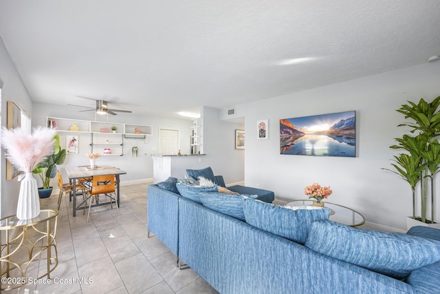 living room featuring light tile patterned floors, a textured ceiling, and ceiling fan