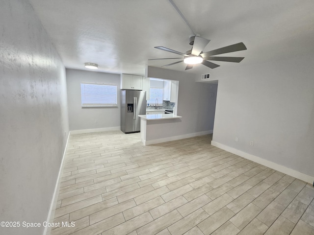 unfurnished living room featuring ceiling fan, sink, and light hardwood / wood-style flooring