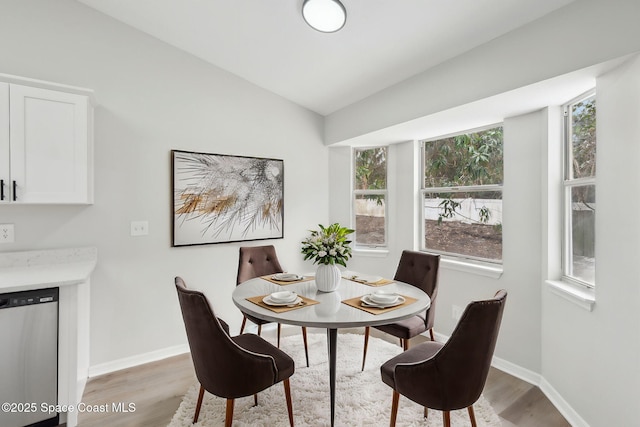 dining space featuring light hardwood / wood-style flooring, a healthy amount of sunlight, and vaulted ceiling