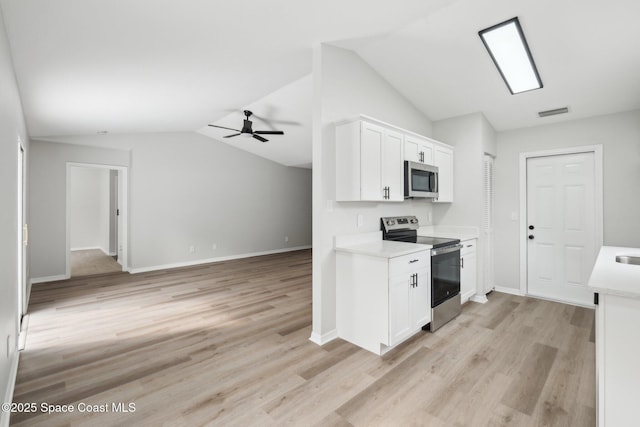 kitchen with lofted ceiling, stainless steel appliances, light hardwood / wood-style floors, and white cabinets