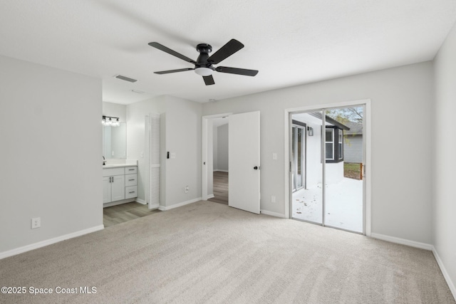 unfurnished bedroom featuring ceiling fan, ensuite bath, access to exterior, and light carpet