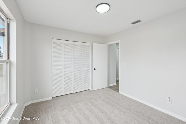 unfurnished bedroom featuring light carpet and a closet