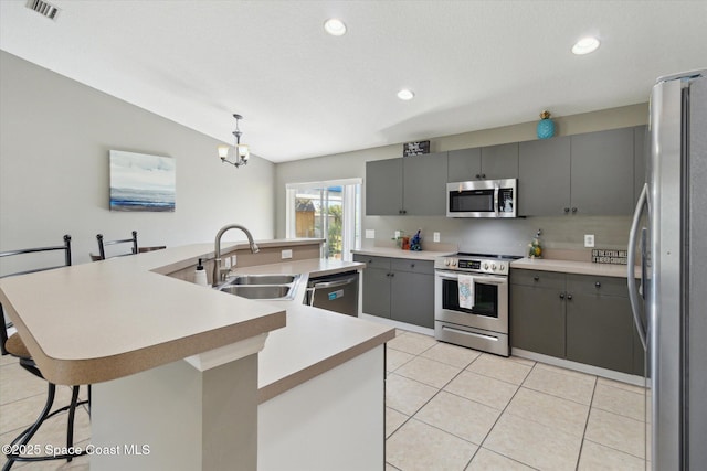 kitchen featuring stainless steel appliances, a center island with sink, sink, and gray cabinetry