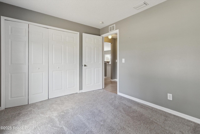 unfurnished bedroom featuring light carpet and a closet