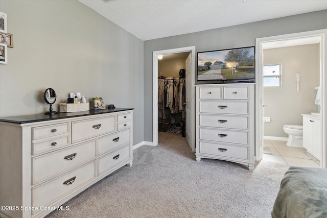 carpeted bedroom with a walk in closet, connected bathroom, a textured ceiling, and a closet