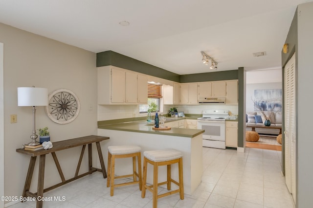 kitchen featuring a breakfast bar, electric range, track lighting, kitchen peninsula, and decorative backsplash