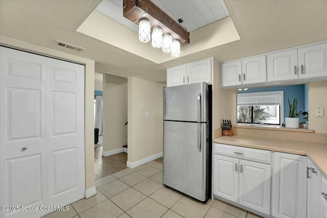 kitchen featuring white cabinetry, light tile patterned floors, and stainless steel refrigerator