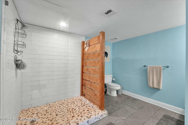 bathroom with a tile shower, tile patterned flooring, and toilet