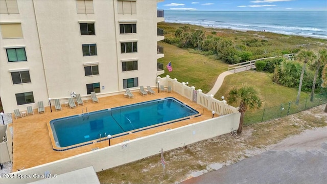 view of swimming pool with a patio, a water view, and a view of the beach