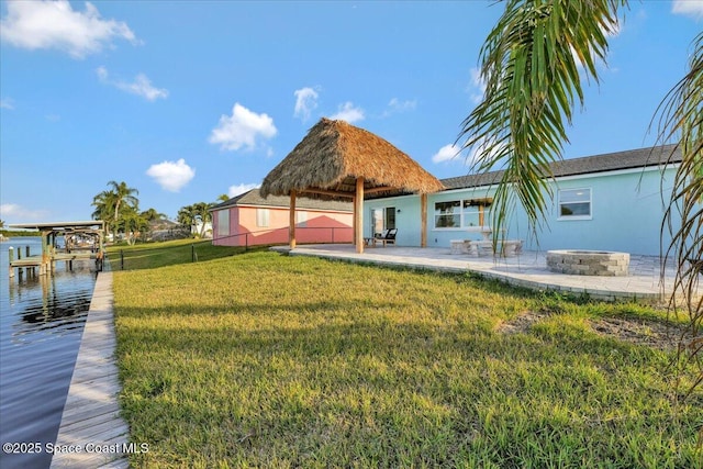 rear view of house with a fire pit, a yard, a gazebo, a patio, and a water view