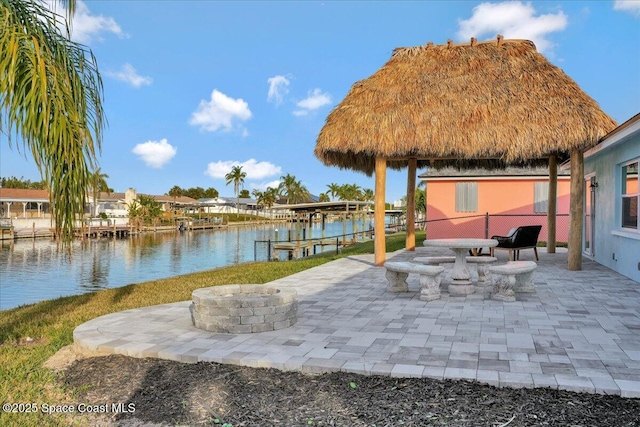 view of dock with a water view, a patio area, and a fire pit