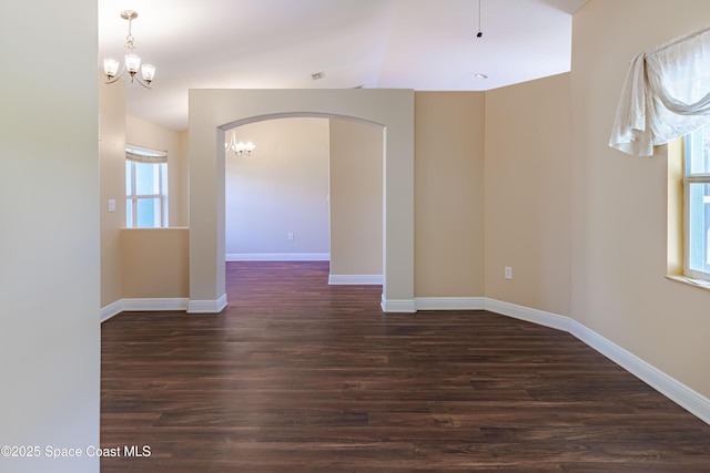 spare room with dark wood-type flooring and a notable chandelier