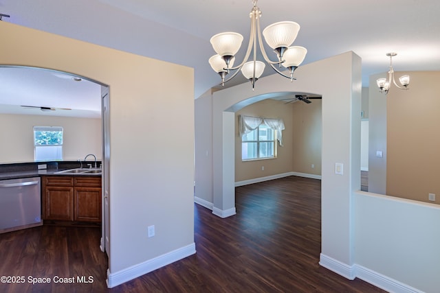 unfurnished dining area featuring dark wood-type flooring, ceiling fan with notable chandelier, and sink