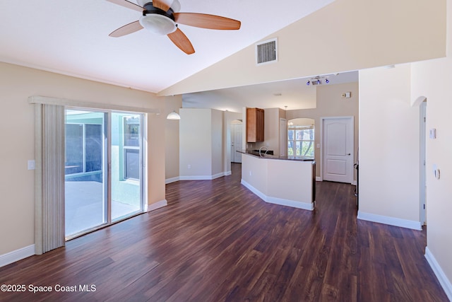 unfurnished living room with dark wood-type flooring, ceiling fan, and vaulted ceiling