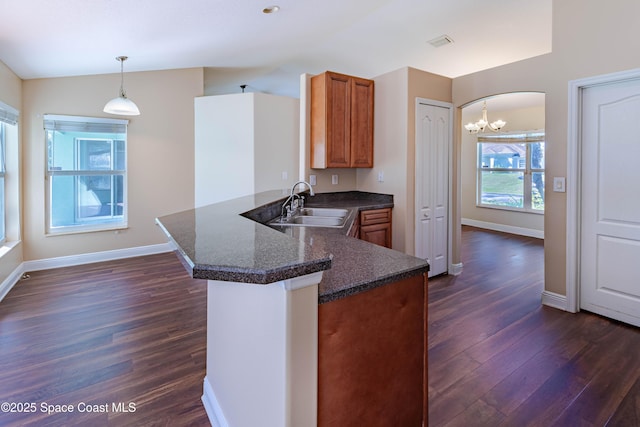 kitchen featuring dark hardwood / wood-style floors, sink, dark stone counters, hanging light fixtures, and kitchen peninsula