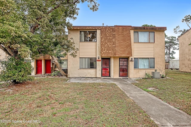 view of front of home with central AC unit and a front yard