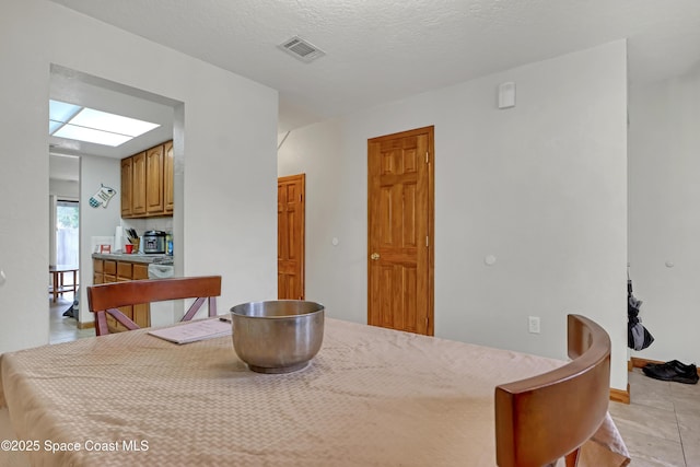 tiled dining room featuring a textured ceiling