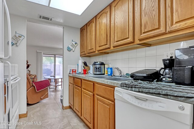 kitchen featuring light tile patterned flooring, sink, fridge, dishwasher, and decorative backsplash