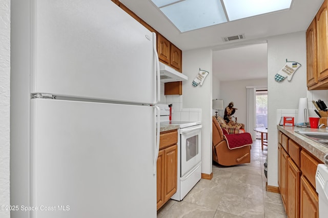 kitchen featuring backsplash, white appliances, and light tile patterned flooring