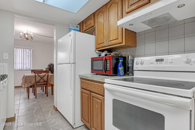 kitchen featuring a chandelier, white appliances, and decorative backsplash