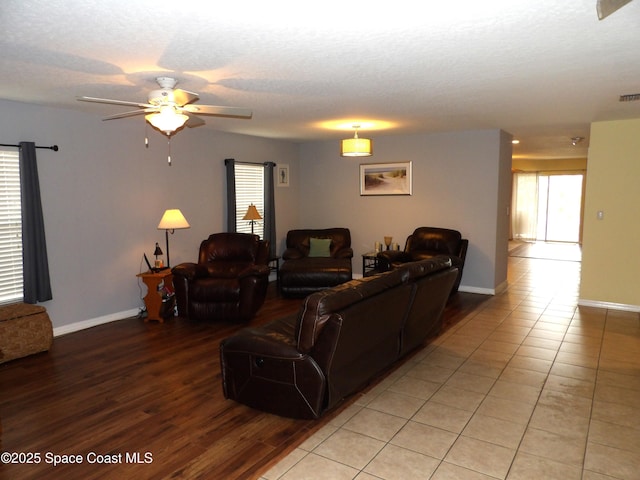 living room featuring ceiling fan, a textured ceiling, and light hardwood / wood-style floors