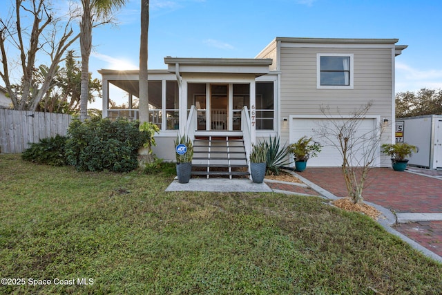 rear view of property featuring a garage, a yard, and a sunroom