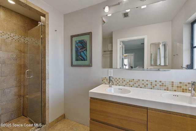 bathroom with vanity, decorative backsplash, a shower with door, and tile patterned floors