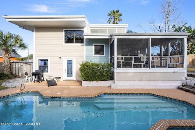 rear view of house with a fenced in pool, a patio, and a sunroom