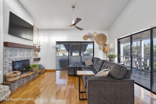 living room featuring ceiling fan, wood-type flooring, a fireplace, and lofted ceiling