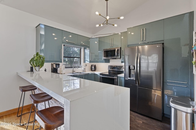 kitchen featuring sink, a breakfast bar area, kitchen peninsula, stainless steel appliances, and dark wood-type flooring