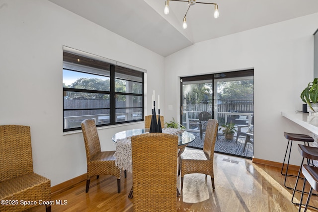 dining space with lofted ceiling, hardwood / wood-style flooring, and a healthy amount of sunlight