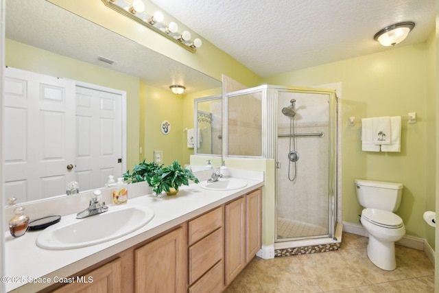 bathroom with tile patterned flooring, vanity, walk in shower, toilet, and a textured ceiling