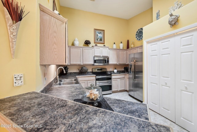 kitchen featuring sink, light tile patterned floors, appliances with stainless steel finishes, light brown cabinetry, and kitchen peninsula