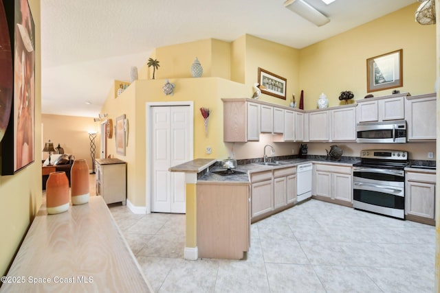 kitchen featuring sink, light tile patterned floors, appliances with stainless steel finishes, high vaulted ceiling, and kitchen peninsula