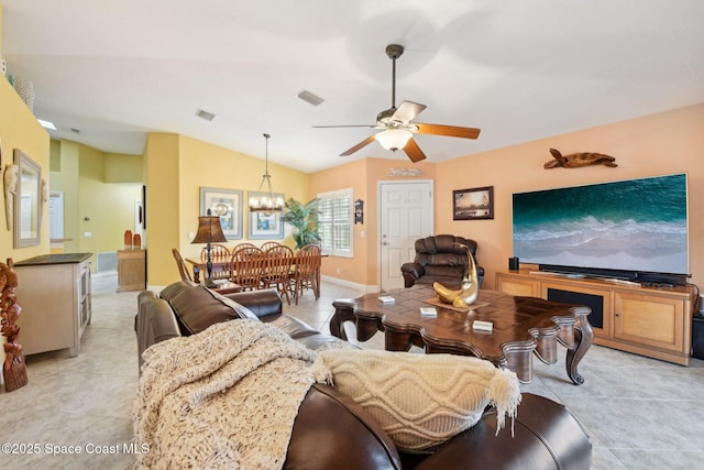 living room with lofted ceiling, ceiling fan with notable chandelier, and light tile patterned floors