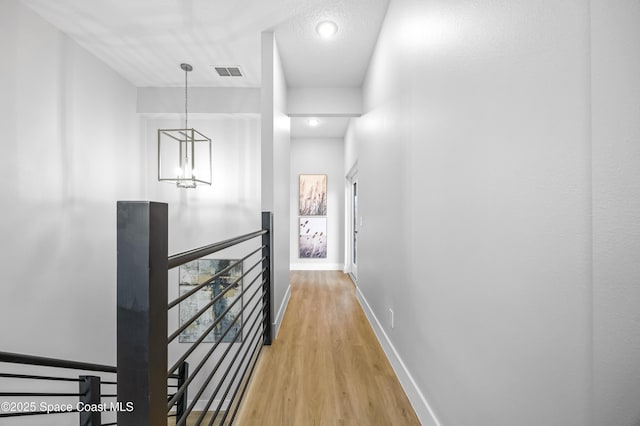 hallway with an inviting chandelier, hardwood / wood-style flooring, and a textured ceiling