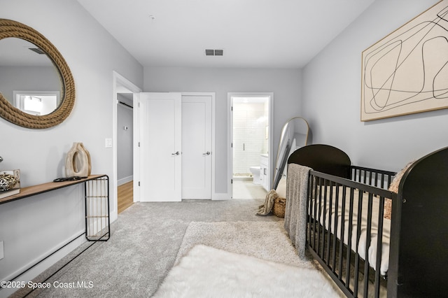 bedroom with light colored carpet, ensuite bath, and a crib