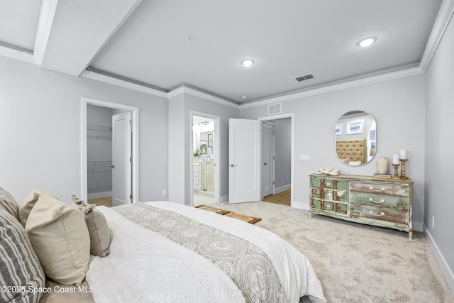 bedroom with crown molding, a walk in closet, light colored carpet, and ensuite bathroom