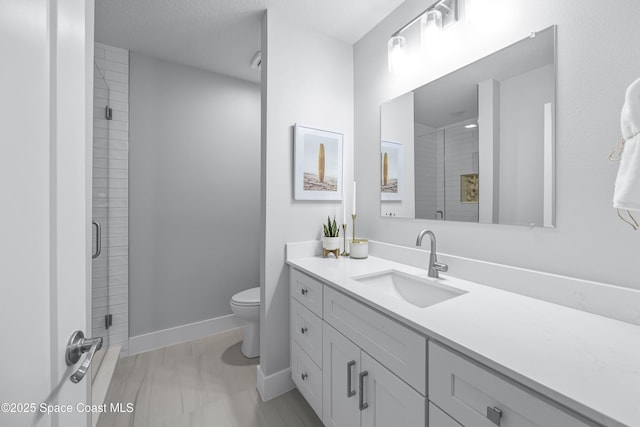 bathroom with vanity, toilet, a textured ceiling, and walk in shower